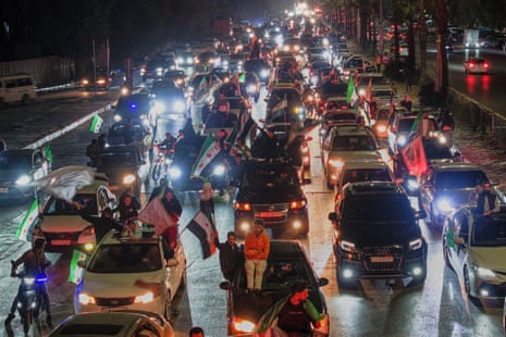 People wave flags in traffic in Damascus