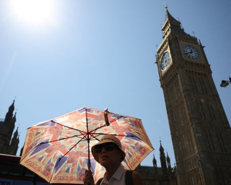 A woman covers from the sun with an umbrella during a heatwave in London, Britain.
