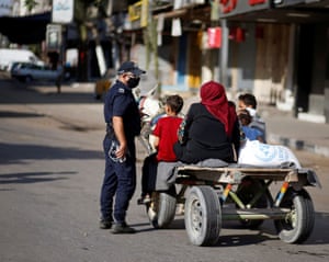 A police officer speaks with Palestinians riding a donkey-drawn cart during lockdown after Gaza reported its first cases of Covid-19 in the general population.