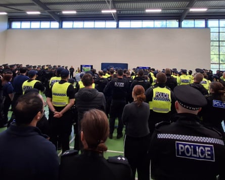 A laege number of police officers being briefed in a hall
