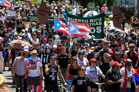 a group of people walking through street, waving flags and signs