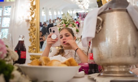 Maria on her phone during her first communion lunch that will last almost the whole day.
