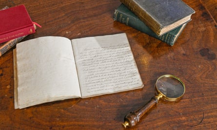 The open manuscript next to a magnifying glass and stacks of books