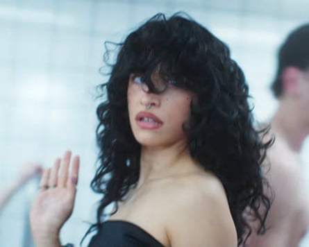 Odessa A’Zion with her hair falling over her face, wearing a back top