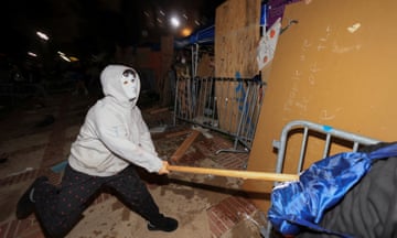 a man in a white hoodie and white face mask strikes a barricade