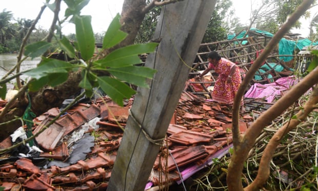 A woman clears debris from her home damaged by Cyclone Bulbul in Bakkhali, West Bengal.