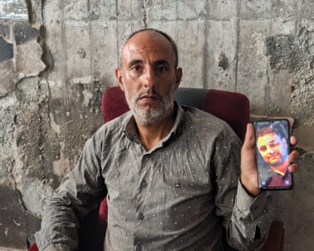 Al-Yazji holds up a picture of his brother on his phone