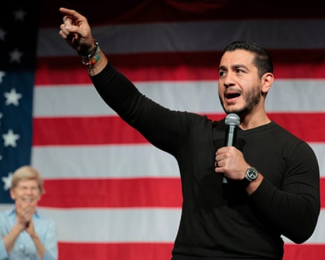 Abdul El-Sayed speaks into a microphone, pointing upward during a campaign town hall