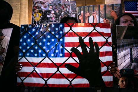 hand holding fence, american flag in the background
