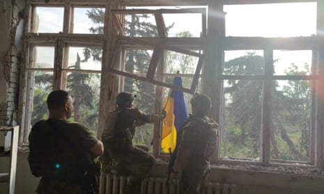 Ukrainian soldiers place a Ukrainian flag in a building in Blahodatne village