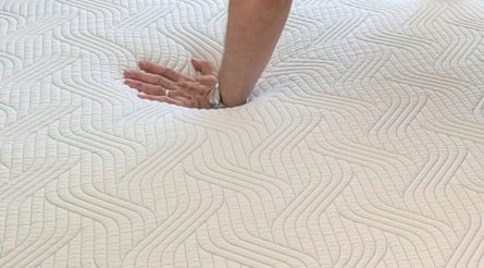 Hand pressing down into the middle of the Tempur Pro Plus SmartCool mattress.