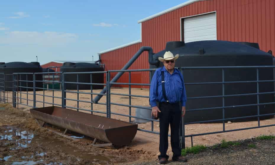 Bob Durham stands next to four of six rainwater collection tanks at his ranch near Abernathy, Texas.