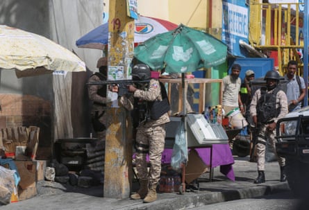 A policeman wearing body armour aims a rifle on a market street in Haiti