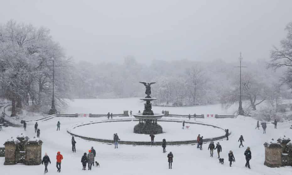 People gather near the Bethesda Fountain as snow falls in Central Park in New York City on Sunday.