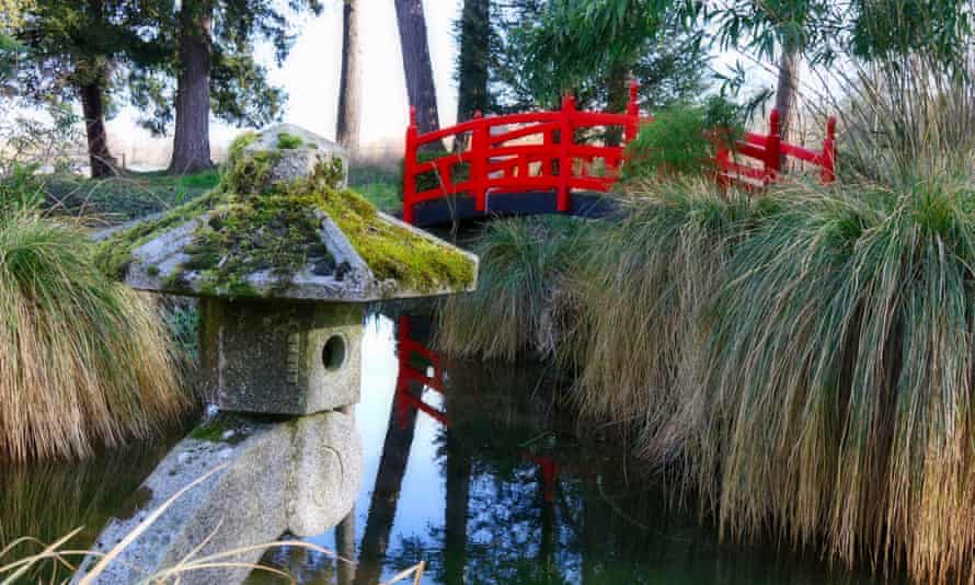 Red Japanese bridge over water in garden