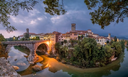 Old bridge over a river in an north Italian town at dusk.