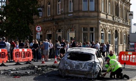 A burnt-out car is removed after a night of violent anti-immigrant demonstrations in Sunderland.