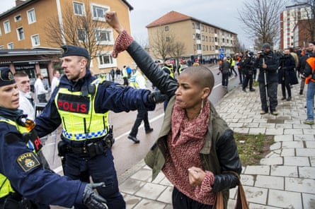 Two police gesture for Tess Apslund to stay where she stands, as she raises her fist