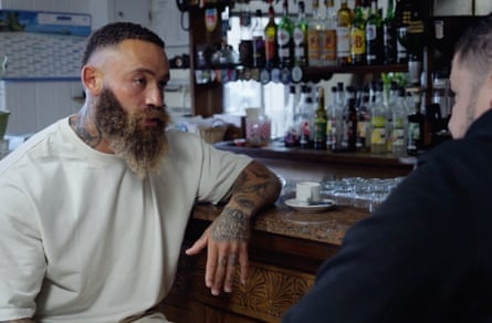 Cain interviewing a man while seated at a bar