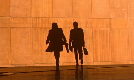 Two office workers silhouetted against the large orange wall of the Credit Lyonnais Bank at Broadgate in London.