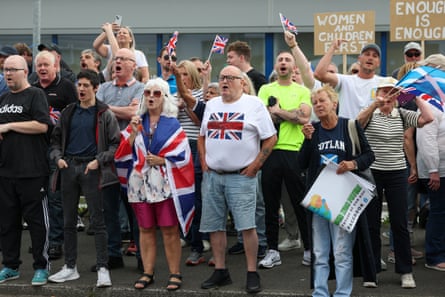 Anti-immigration protesters arrayed along a pavement, several with union flags and holding signs reading ‘Enough is enough’ and ‘Women and children first’