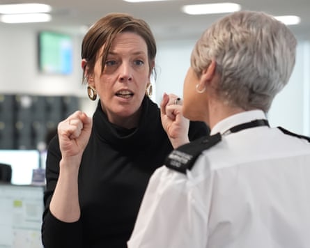 Jess Phillips gestures while speaking to a woman in police uniform