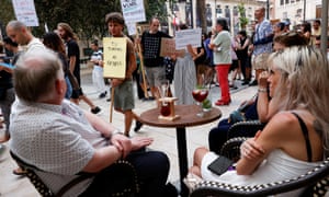 Tourists sitting in cafe watch as locals protest against tourism in Alicante