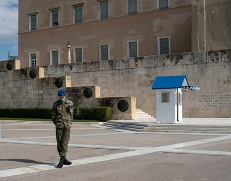 A Greek Presidential Guard wearing a protective face mask stands in front of the Unknown Soldier Tomb in Athens.