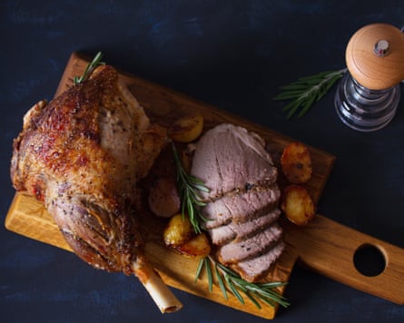 Roast leg of lamb with potatoes and rosemary on serving wooden board. View from above, top view