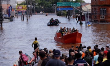 People crowded in boats floating on flood waters in Canoas