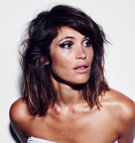 Gemma Arterton with bare shoulders, tanned, with pale pink lipstick and black and silver eye makeup
