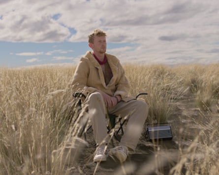 A man sits in a field in a grassy desert from This is How the World Ends.