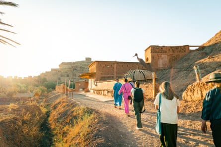 In the historic village of Aït Benhaddou with Intrepid Travel in Morocco. A line of tourists follow a guide along a road in bright sunshine