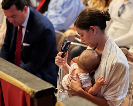 A woman uses a fan while holding a baby amid heatwave, during Mass led by Pope Leo on the Solemnity of Saints Peter and Paul, Apostles, in St Peter's Basilica, at the Vatican.