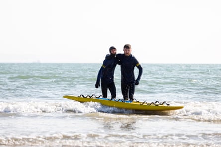 Dean and Shem in wetsuits with a paddleboard