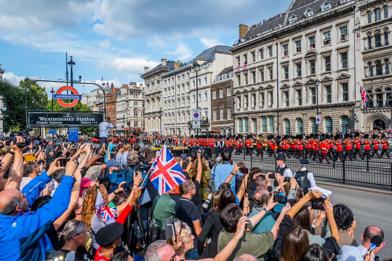 Oamenii privesc procesiunea în timp ce sicriul Reginei este transportat pe o trăsură de tun a trupei regale de artilerie King's Troop Royal Horse Artillery.