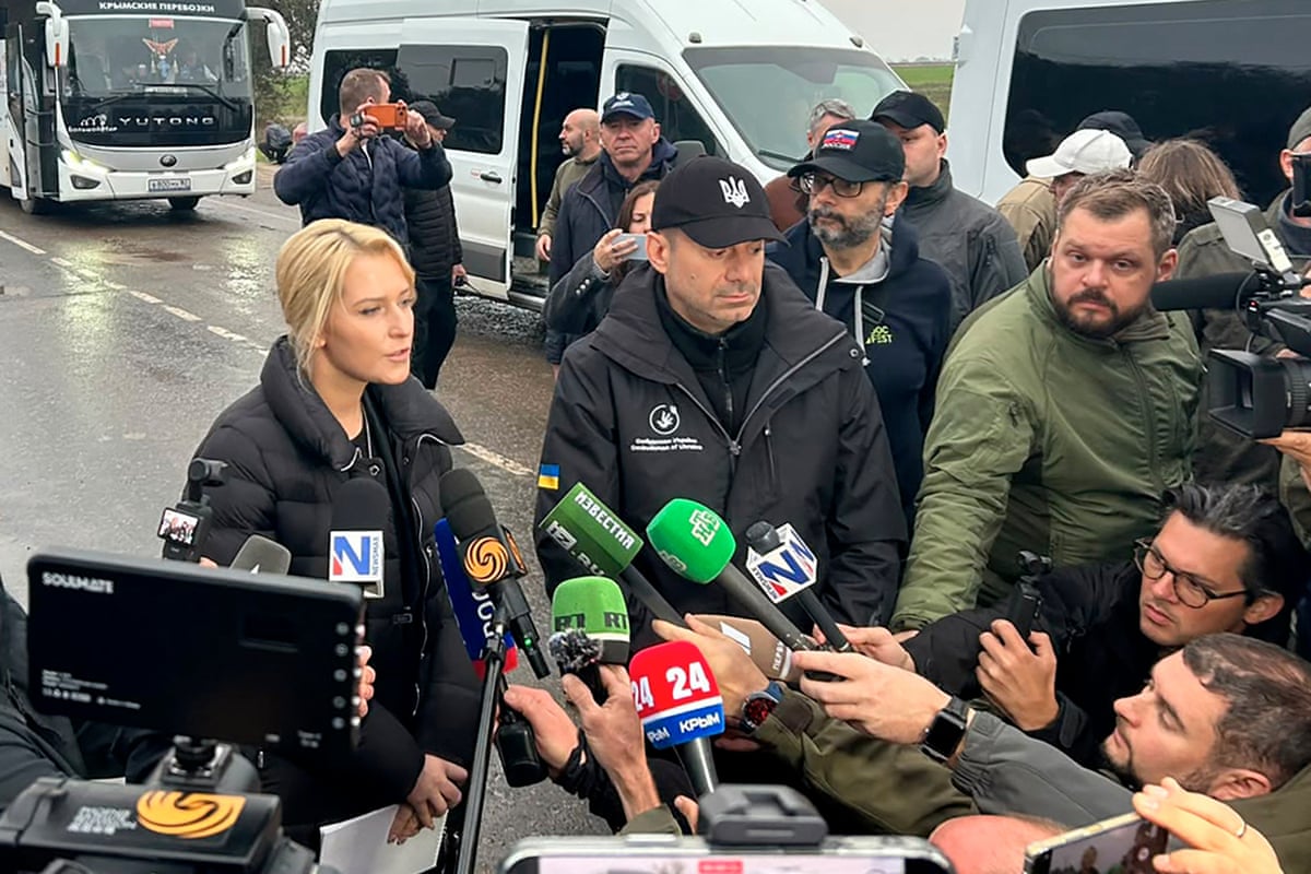 Ukraine’s and Russia’s human rights commissioners speaking to journalists as they arae crowded with microphones