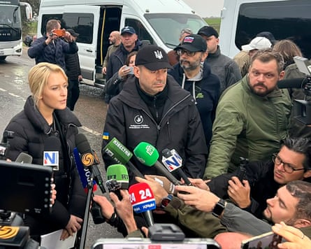 Ukraine's and Russia's human rights commissioners speaking to journalists as they are crowded with microphones