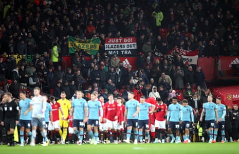 Manchester United fans wave banners saying 'Glazers Out' as the two teams walk out onto the pitch