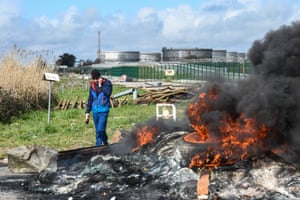 A man walks past a fire in front of oil terminals as workers protest at the Total Energies refinery in Donges