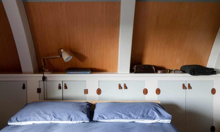 One of the two upstairs bedrooms, showing the top of a double bed with blue bedding and a curved wall behind