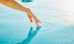 Woman’s hand touching surface of water.