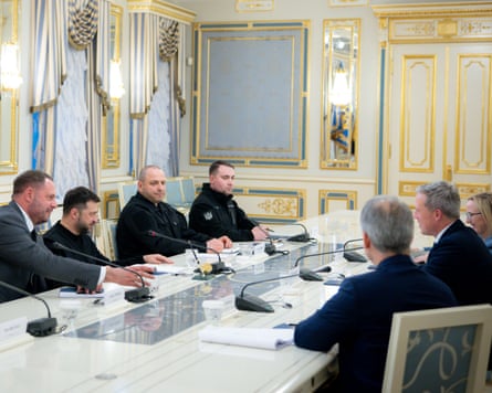 Volodymyr Zelenskyy facing Dan Driscoll with other men at white table