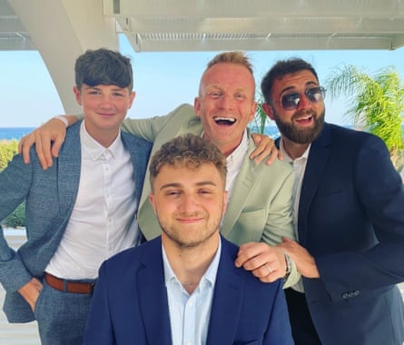 A middle aged man and three younger men wearing suits without ties.