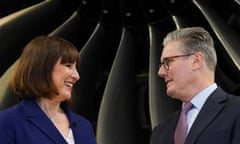 Keir Starmer and Rachel Reeves look at each other standing in front of a large plane engine fan