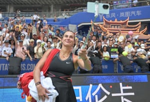 Tennis player Aryna Sabalenka takes a selfie on a selfie stick with fans in the background