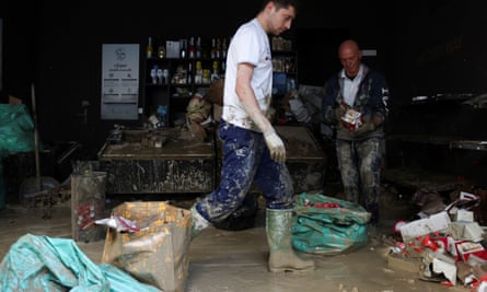 People clean up debris at a coffee shop in Faenza, Italy