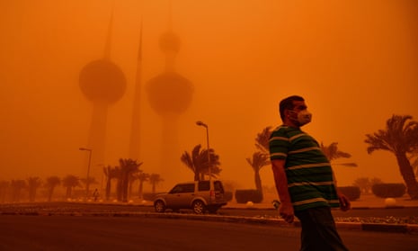 A man walks past the Kuwait Towers shrouded in heavy dust in Kuwait City