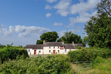 Maenllwyd, a large, whitewashed old pub and outbuildings in a rural setting with trees around it.
