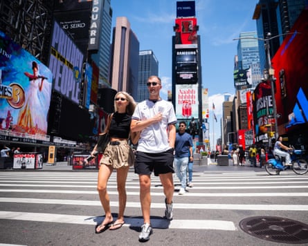 A man wearing an aged England garment walks pinch a women done Times Square successful New York